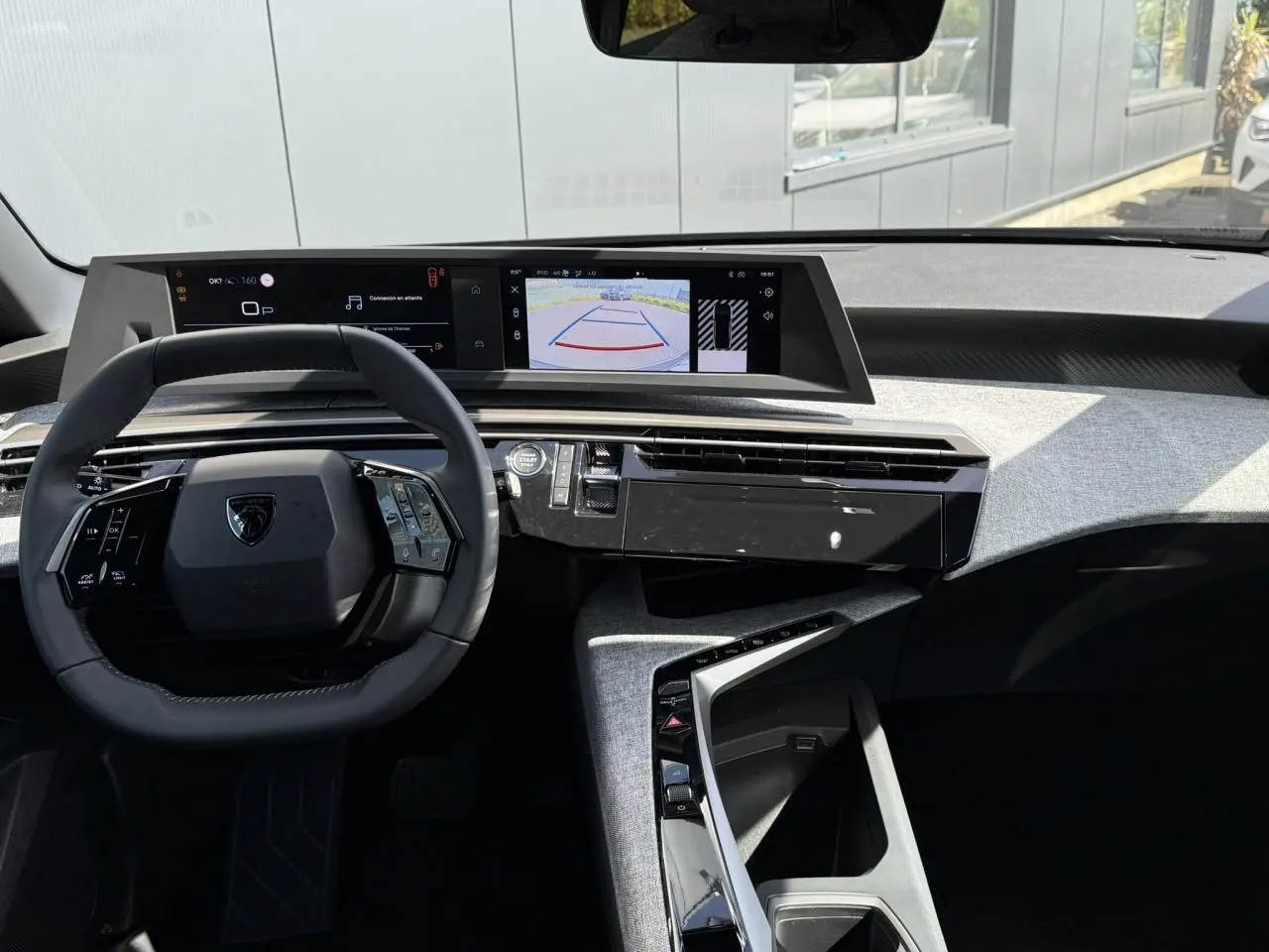 Intérieur Peugeot 3008 Hybrid 2025 vu de face, tableau de bord avec double écran HD et volant compact cuir noir.