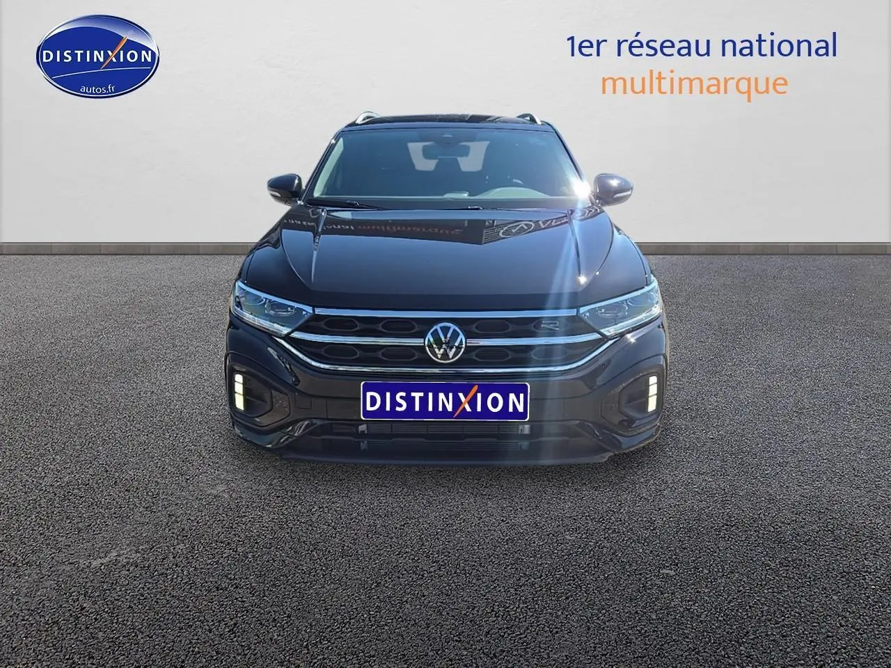 Vue frontale d'un Volkswagen T-Roc noir perle avec calandre R-Line et feux LED allumés sur fond neutre.