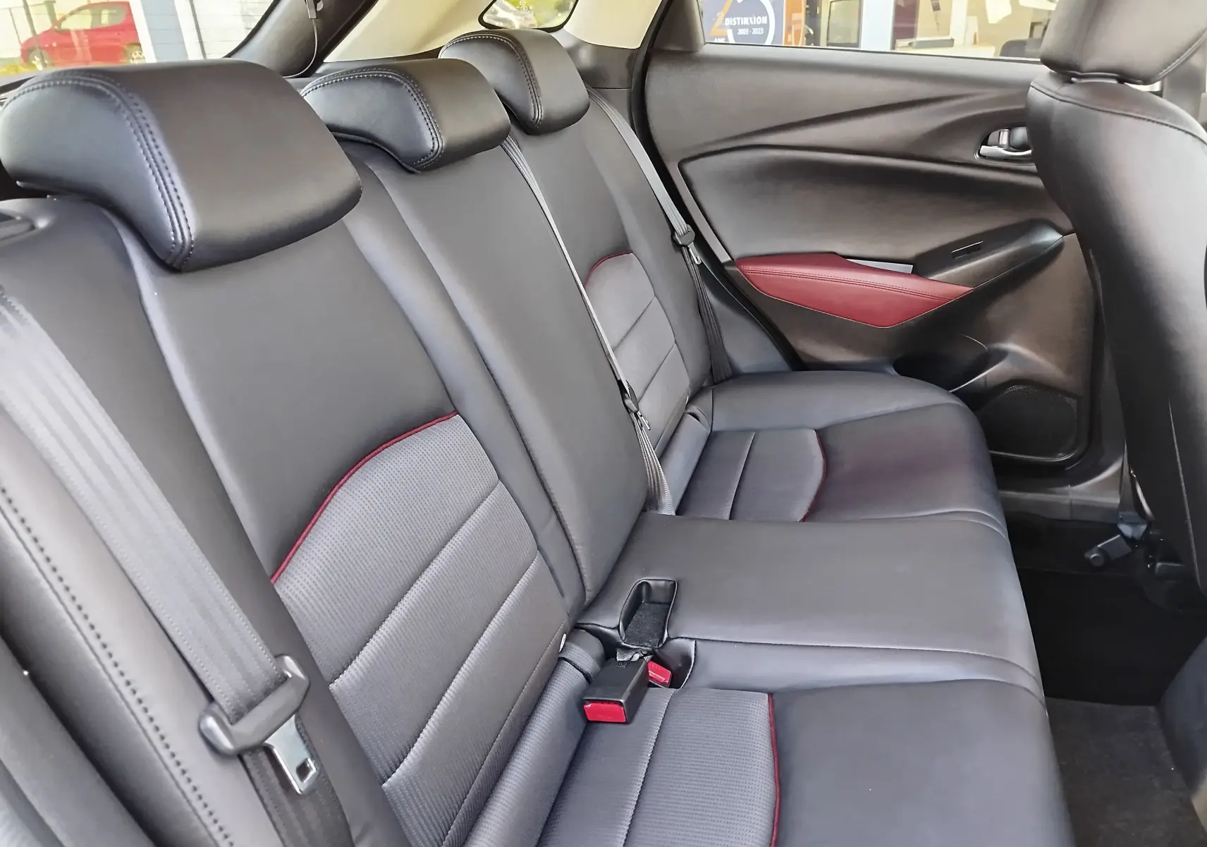 Vue intérieure du siège arrière droit en cuir noir avec surpiqûres rouges du Mazda CX-3 2016 Dynamic Blue Mica.