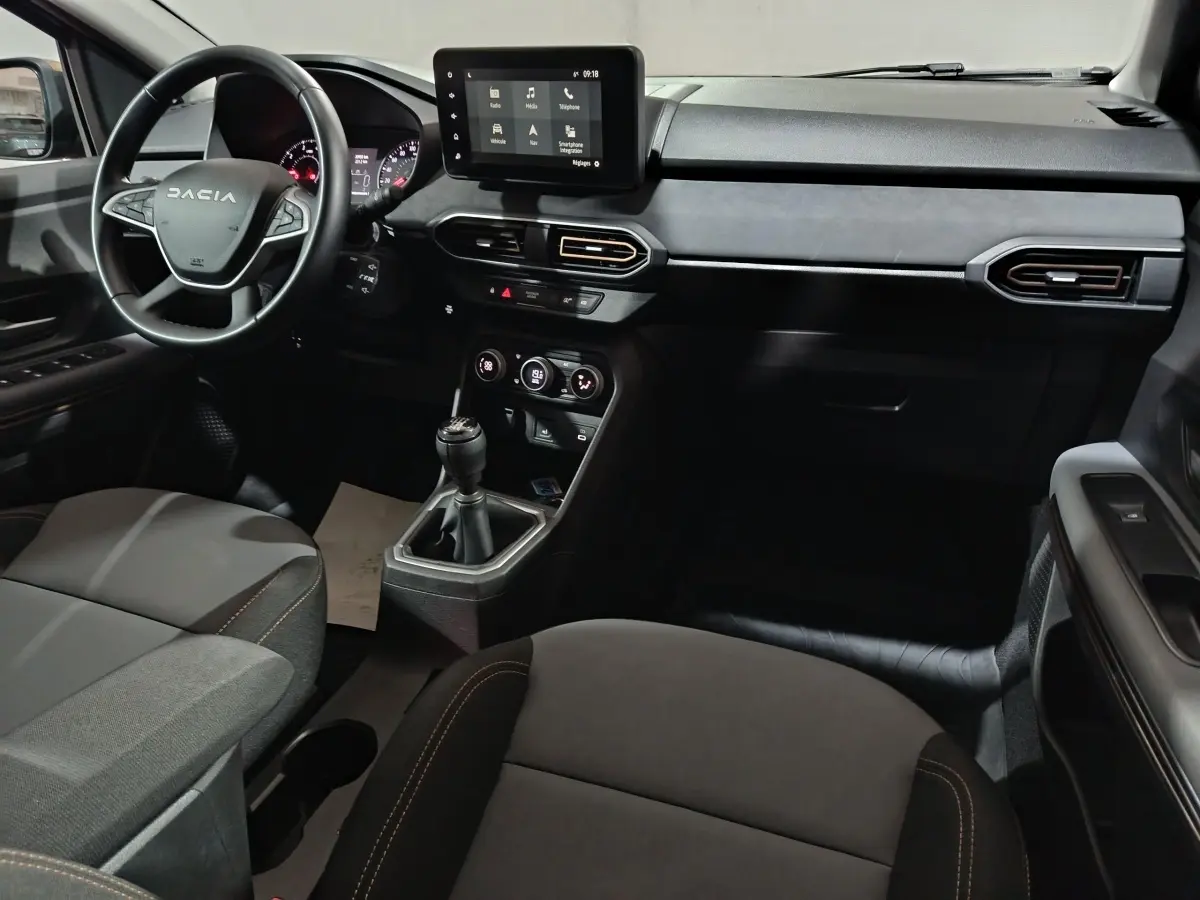Intérieur avant de la Dacia Sandero 2024, vue côté conducteur, volant cuir multifonctions et écran tactile central.