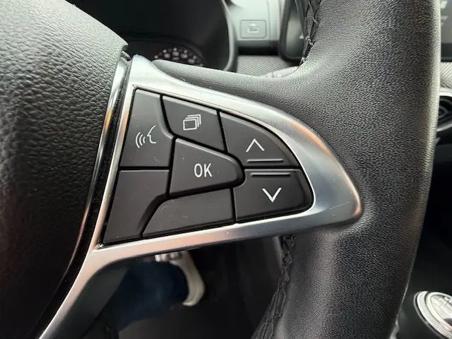 Gros plan sur les commandes au volant côté gauche du Dacia Sandero blanc glacier 2023, version essence manuelle.