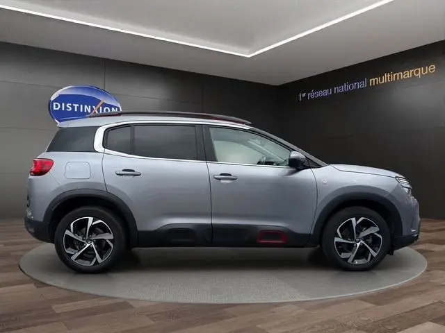 Vue de profil côté gauche d'un Citroën C5 Aircross gris clair avec jantes alliage et détails rouges sur les bas de caisse.