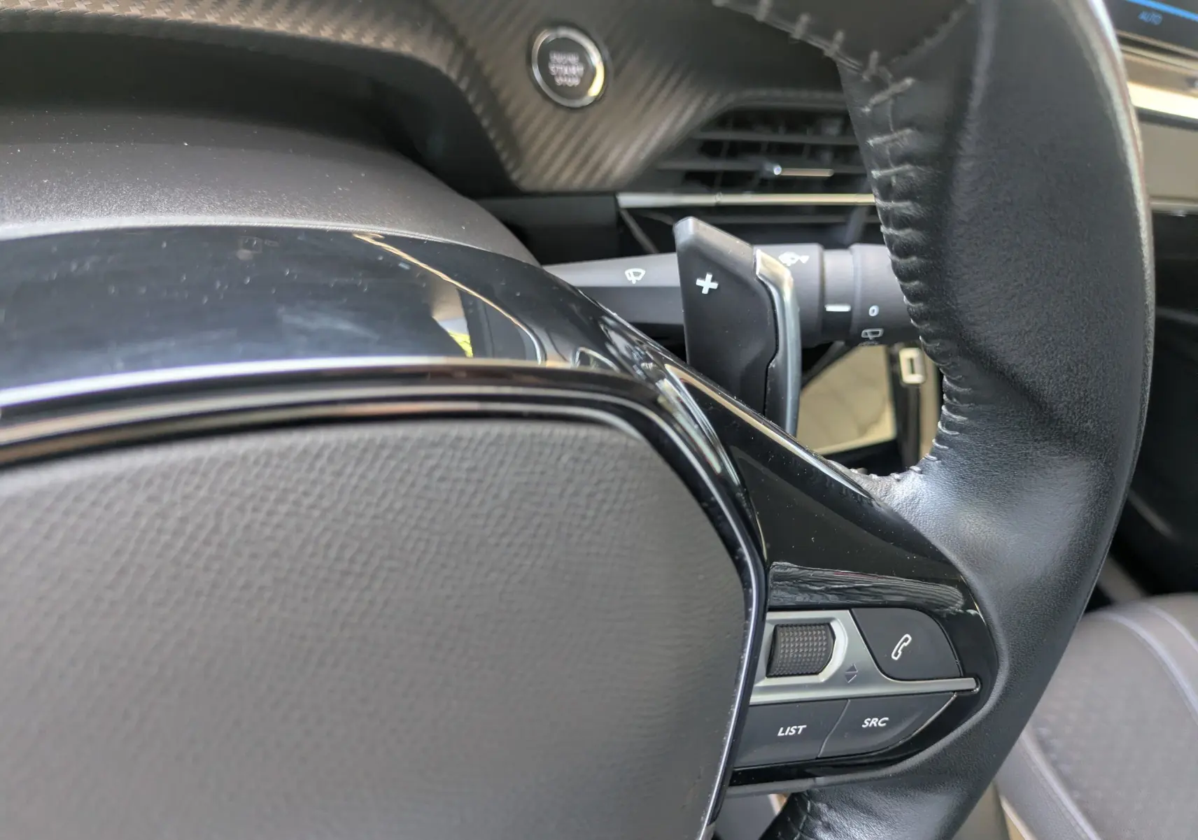 Gros plan sur la partie droite du volant en cuir noir du Peugeot 2008, avec commandes intégrées et palettes au volant.