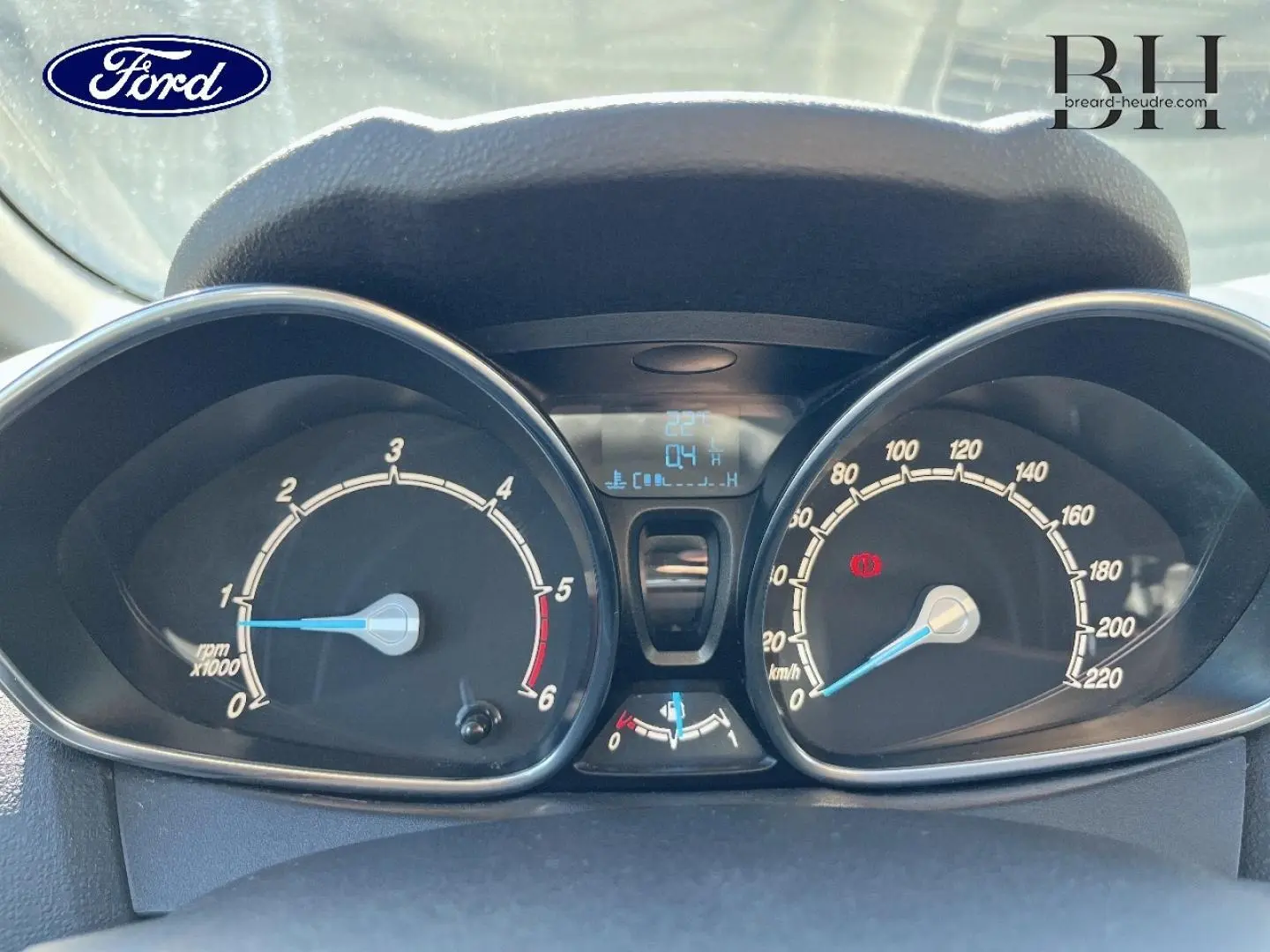 Vue rapprochée du tableau de bord de la Ford Fiesta 2015, avec compte-tours et compteur de vitesse analogiques.