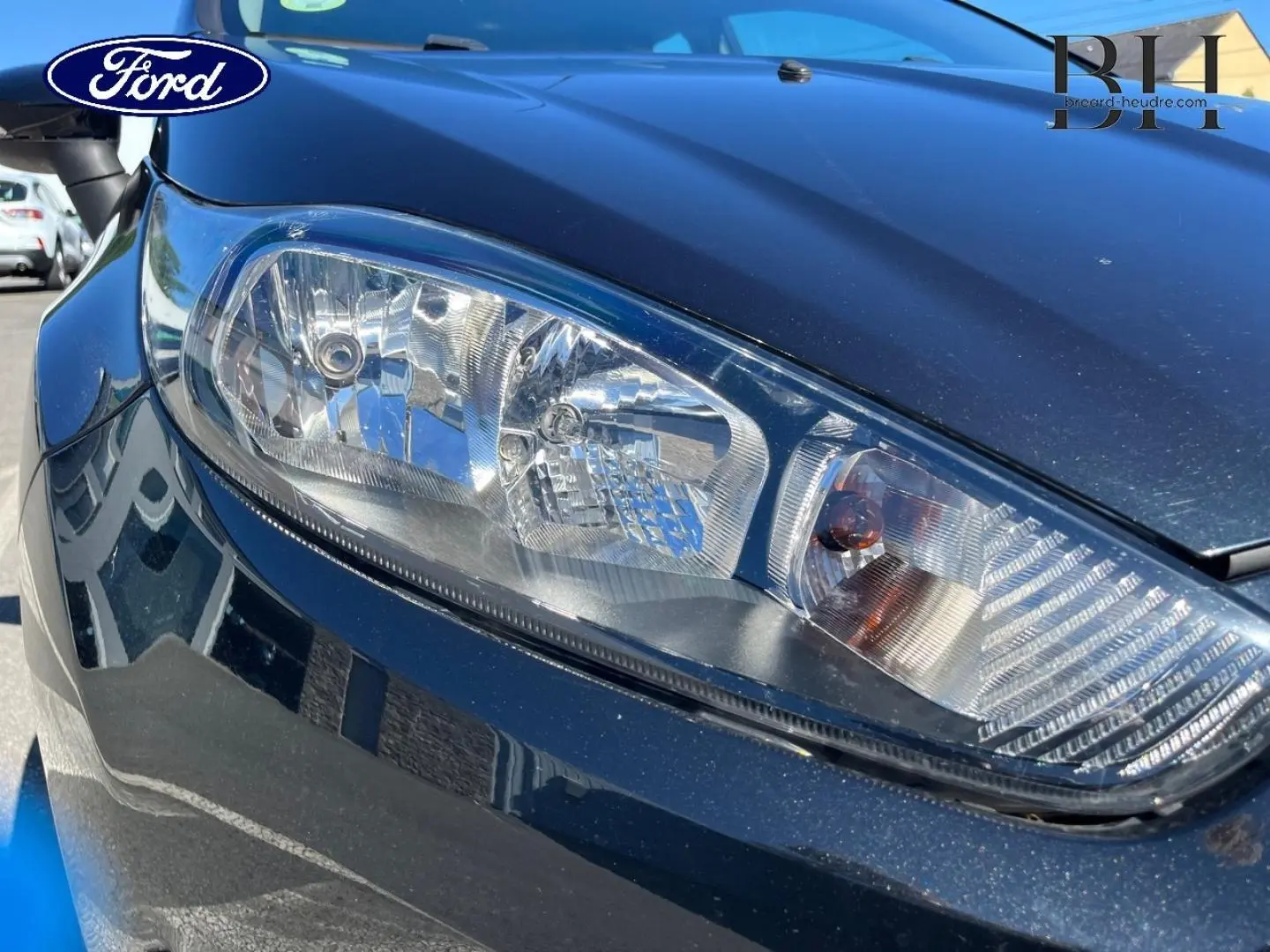 Gros plan sur le phare avant droit d'une Ford Fiesta noire Scala, mettant en valeur les détails du bloc optique.