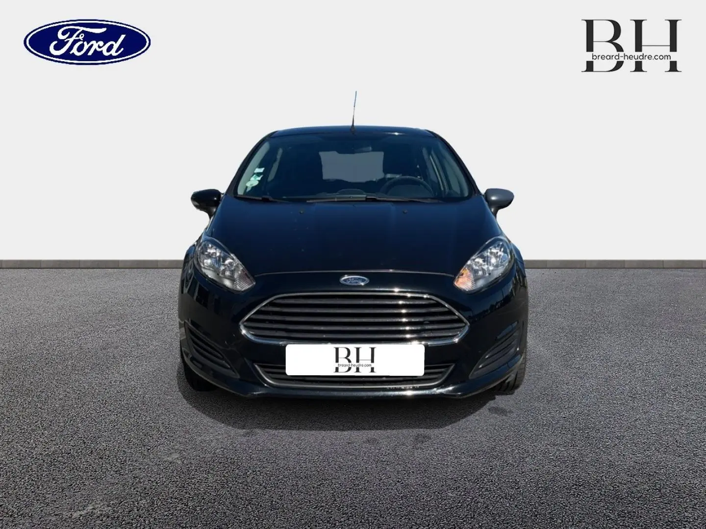 Vue avant d'une Ford Fiesta noire Scala de 2015 avec calandre chromée et phares allumés sur fond neutre.