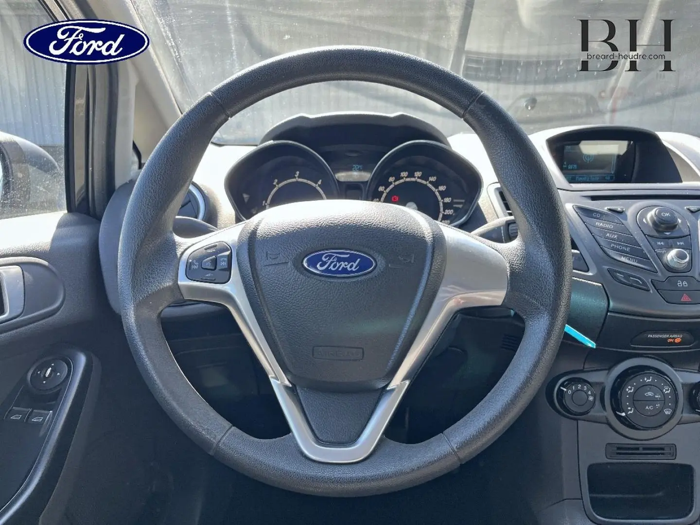 Vue centrée sur le volant multifonction noir de la Ford Fiesta 2015, avec tableau de bord et console centrale visibles.