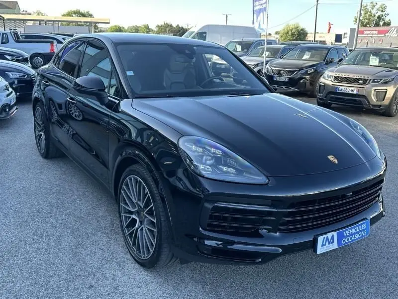 Vue 3/4 avant d'un Porsche Cayenne Coupé noir métal 2020 avec jantes alliage et calandre large en concession.
