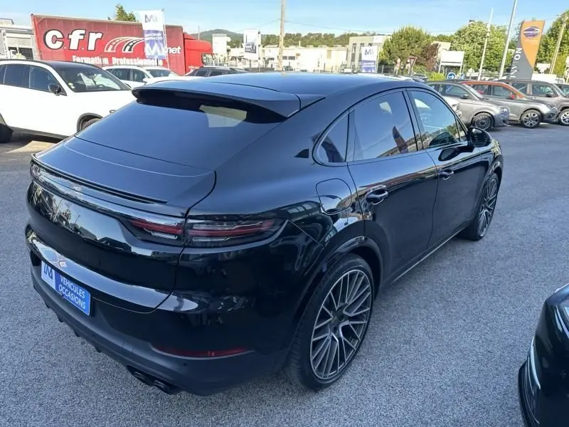 Vue 3/4 arrière droite d'une Porsche Cayenne Coupé 2020 noir métal avec jantes sport et feux arrière allongés.