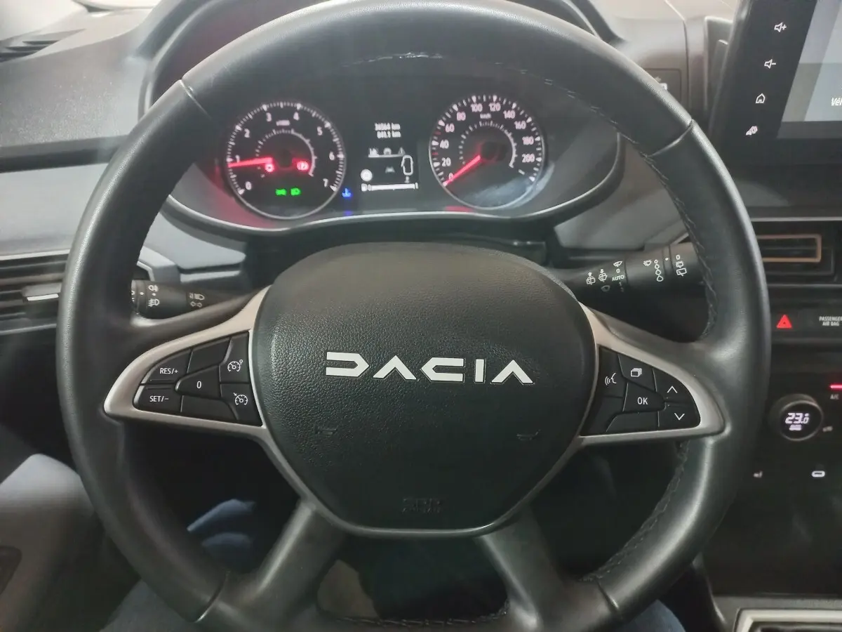 Vue rapprochée du volant cuir synthétique multifonctions de la Dacia Sandero Extreme+ 2024, tableau de bord en arrière-plan.