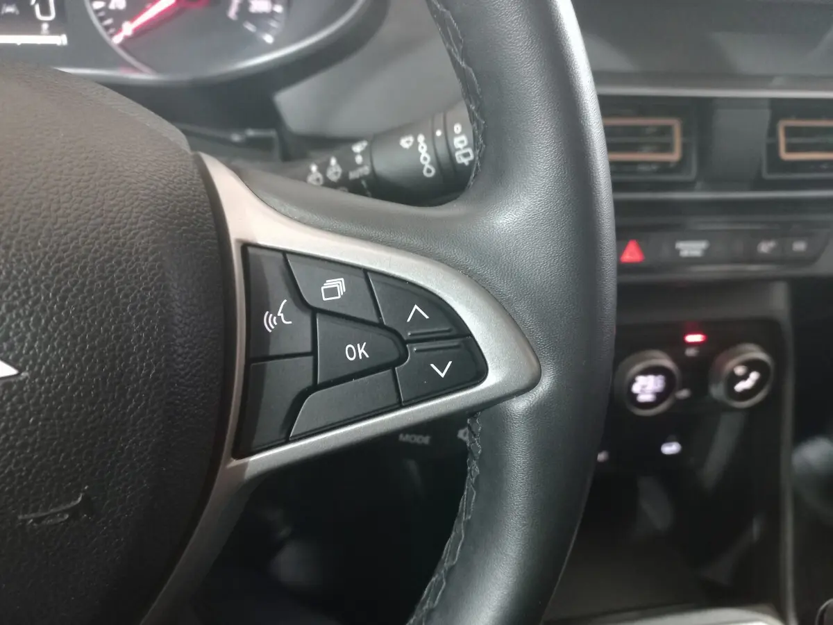 Gros plan sur le volant cuir synthétique noir de la Dacia Sandero Extreme+ 2024 avec commandes multifonctions visibles.