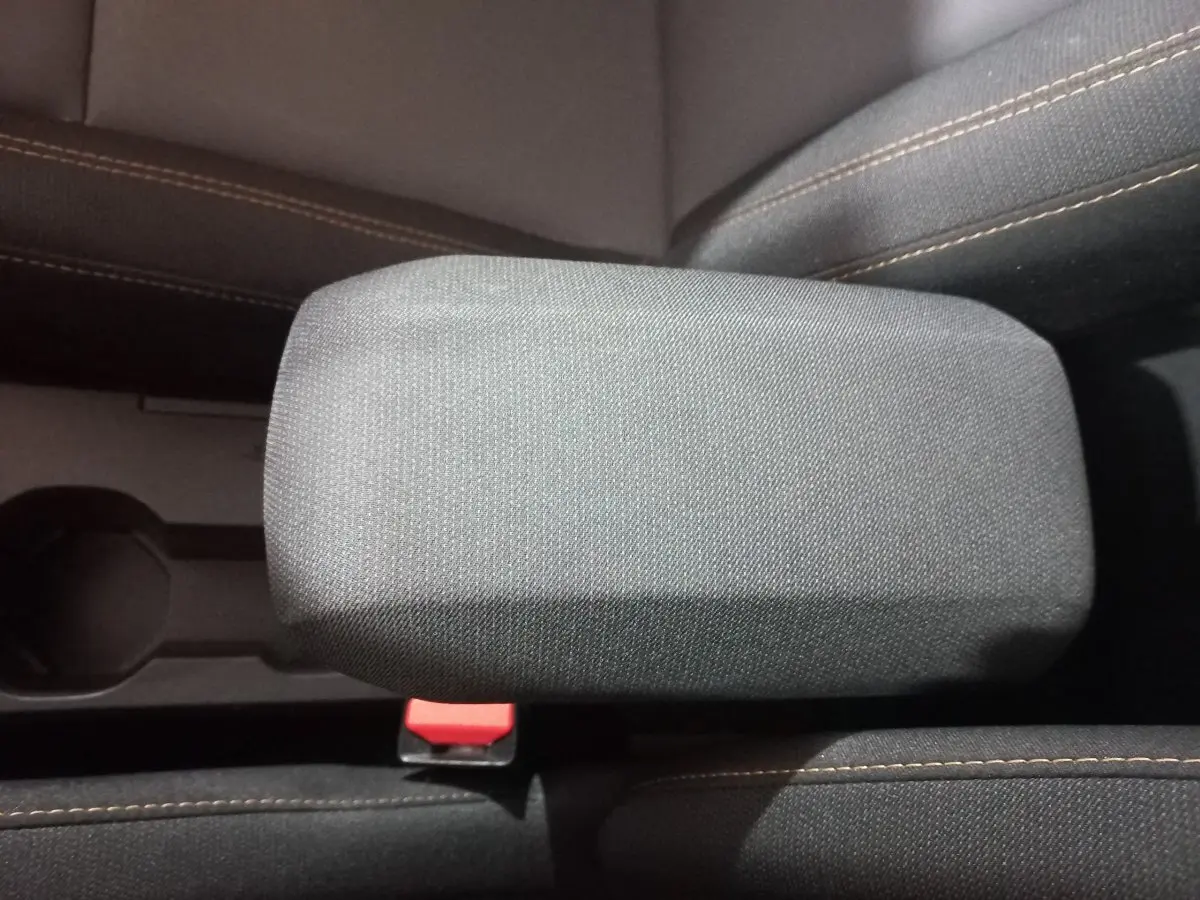 Accoudoir central en tissu gris avec coutures marron sur les sièges avant d'une Dacia Sandero 2024.
