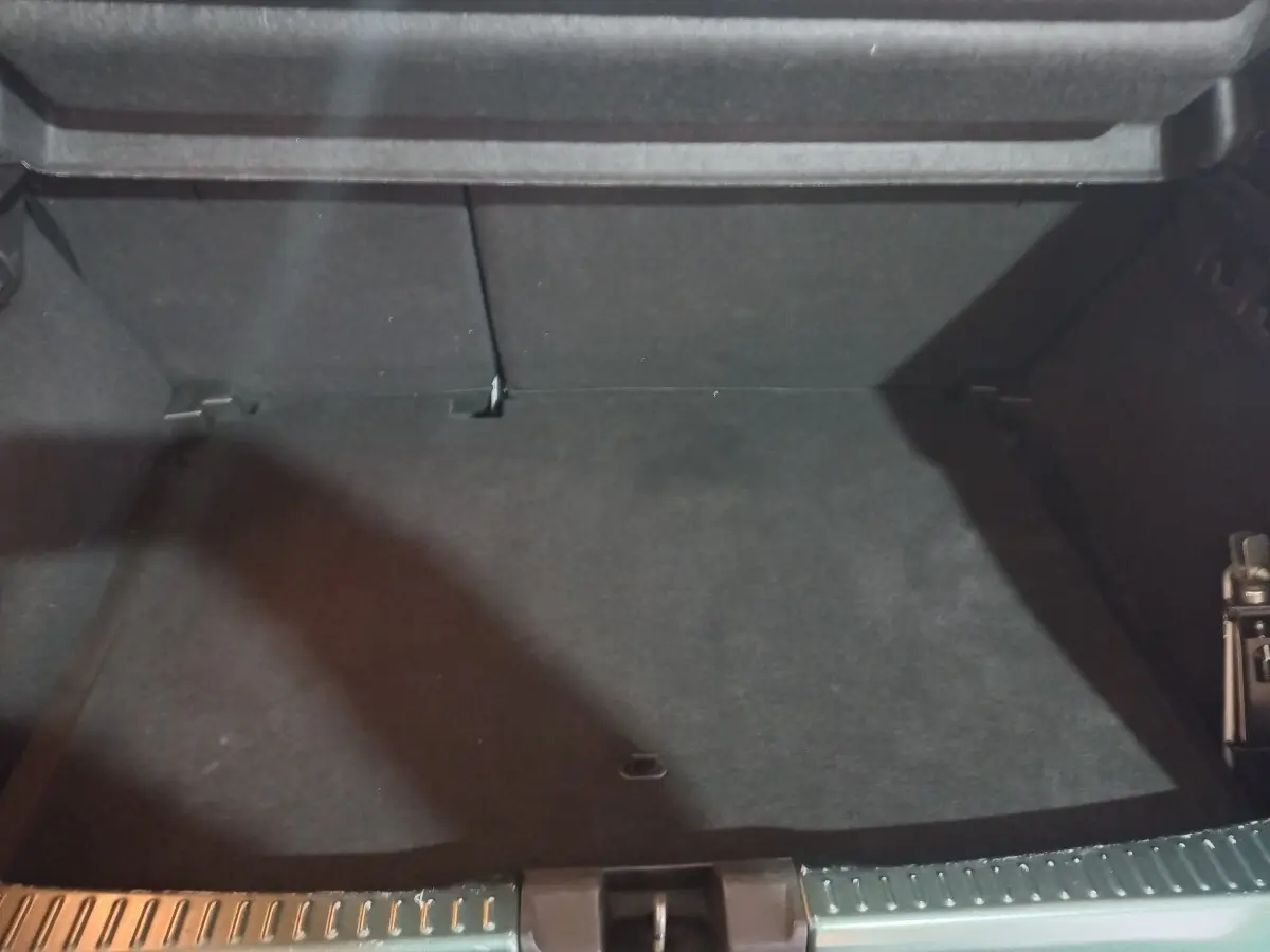 Coffre ouvert d'une Dacia Sandero Extreme+ vert, montrant l'espace de chargement vide et la banquette arrière rabattable.