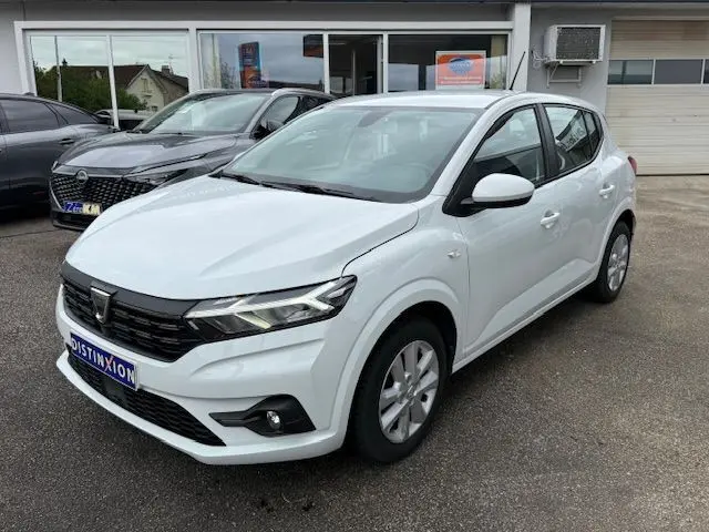 Vue 3/4 avant droite d'une Dacia Sandero 2023 blanc glacier avec calandre noire et feux LED distinctifs.