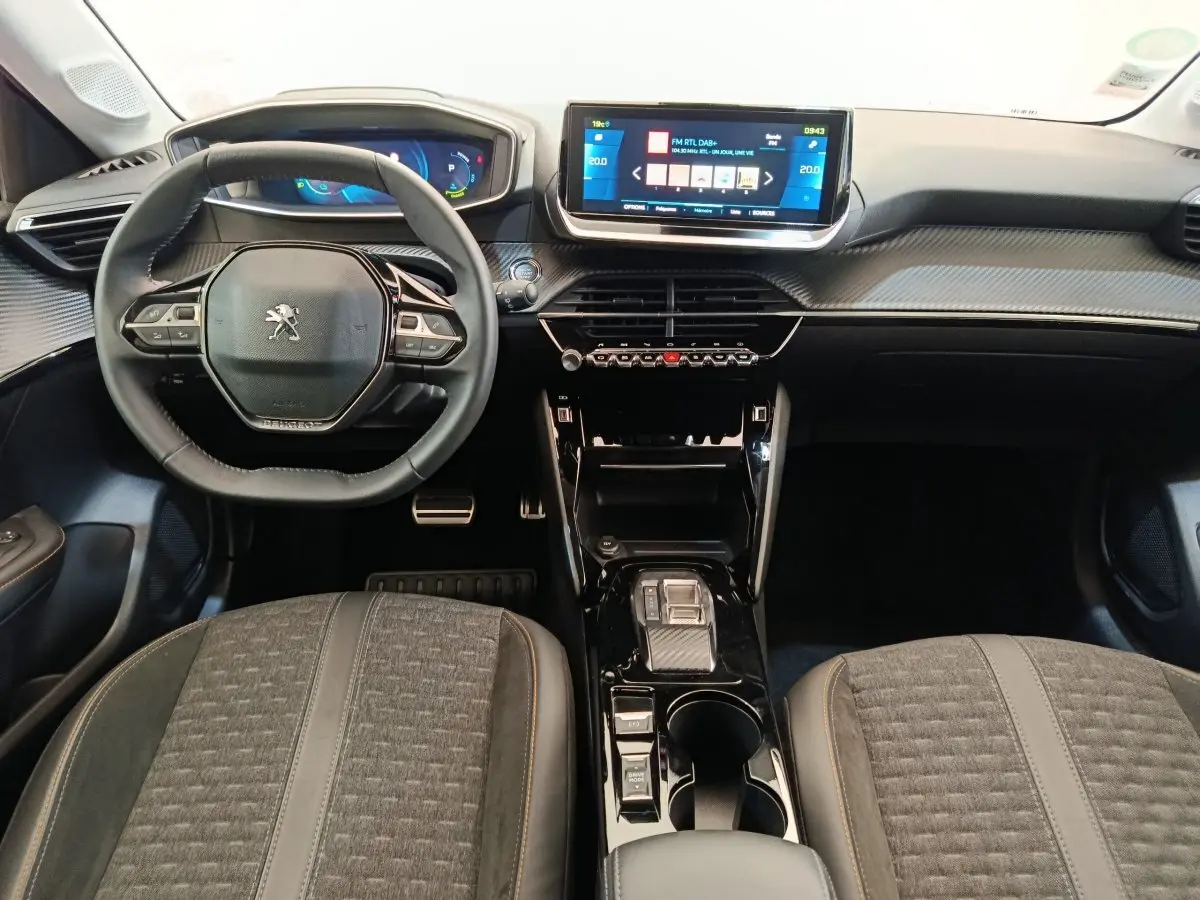 Vue intérieure frontale du tableau de bord et volant cuir de la Peugeot 208 Electrique Roadtrip 2022 avec écran tactile central.