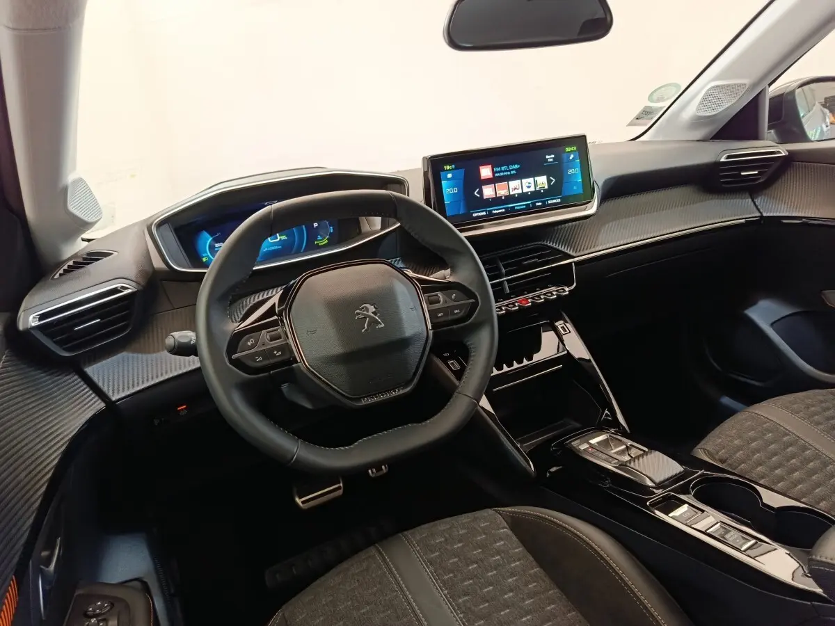 Vue intérieure de face du tableau de bord et volant cuir noir de la Peugeot 208 Electrique Roadtrip 2022 avec écran tactile central.