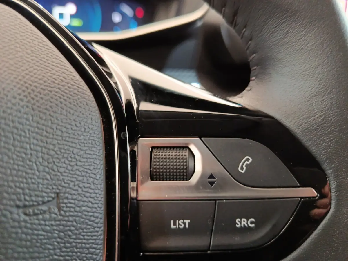 Gros plan sur les commandes au volant cuir noir de la Peugeot 208 Electrique Roadtrip 2022, boutons multifonctions.