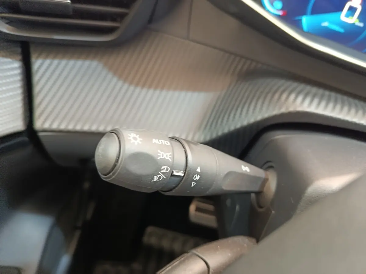 Gros plan sur la commande des phares et clignotants dans l'habitacle du Peugeot 208 électrique gris clair, version 2022.