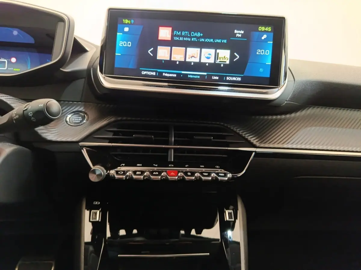 Vue rapprochée du tableau de bord de la Peugeot 208 Electrique Roadtrip 2022 avec écran tactile central allumé.