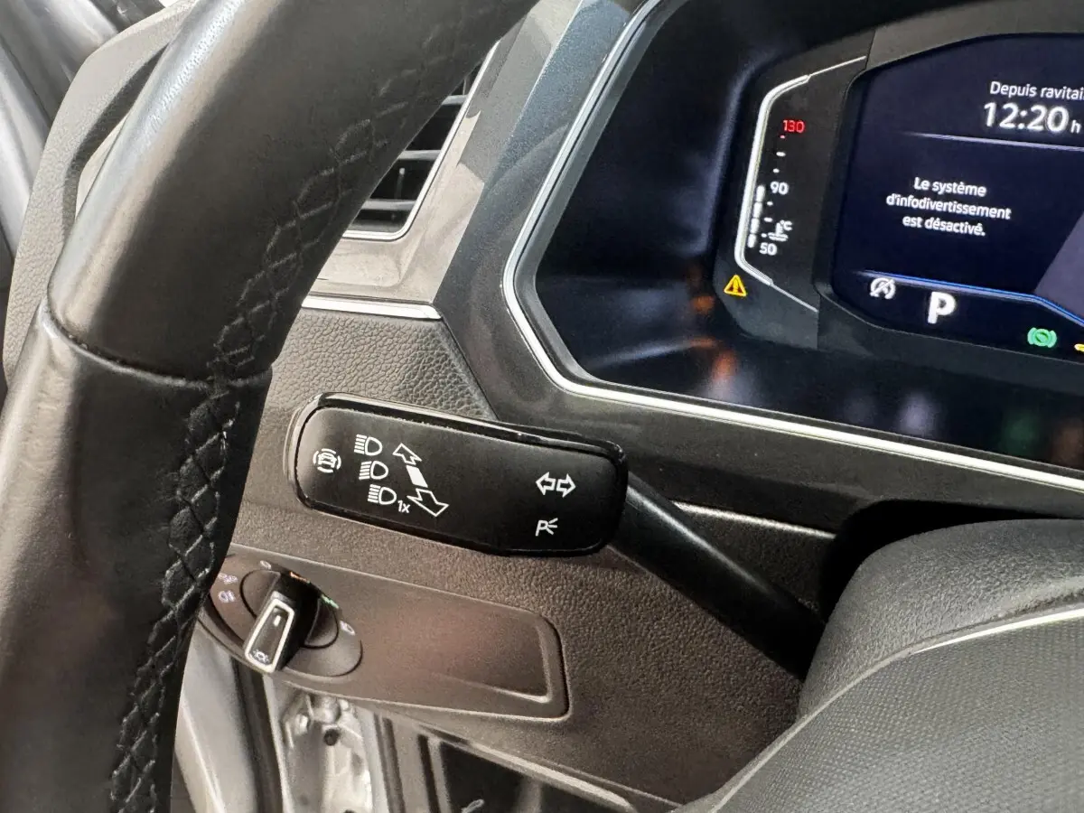 Gros plan sur le volant et le commodo gauche du tableau de bord du Volkswagen Tiguan 1.5 TSI gris clair, affichage numérique visible.