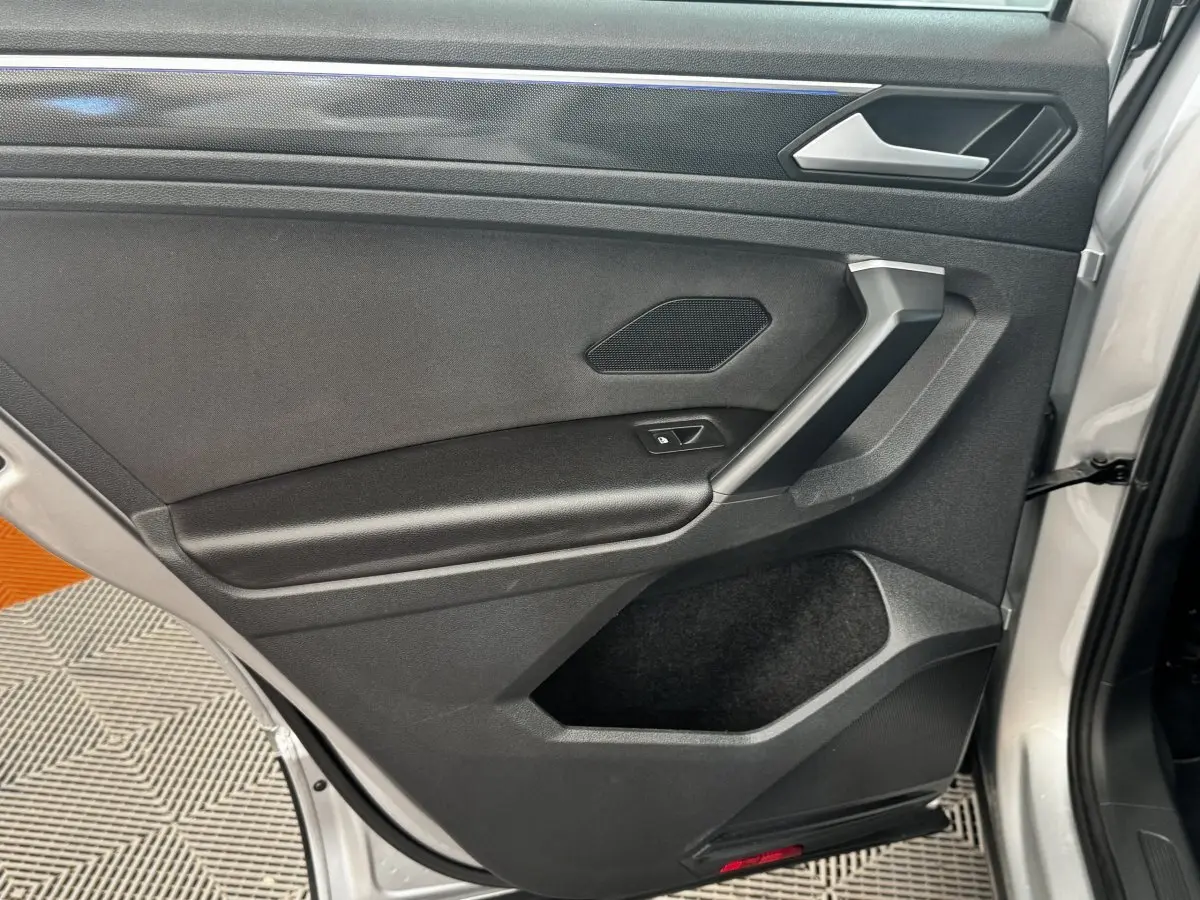 Vue rapprochée de la porte arrière droite gris clair du Volkswagen Tiguan 1.5 TSI 150 DSG7 Elegance avec poignée et haut-parleur intégrés.