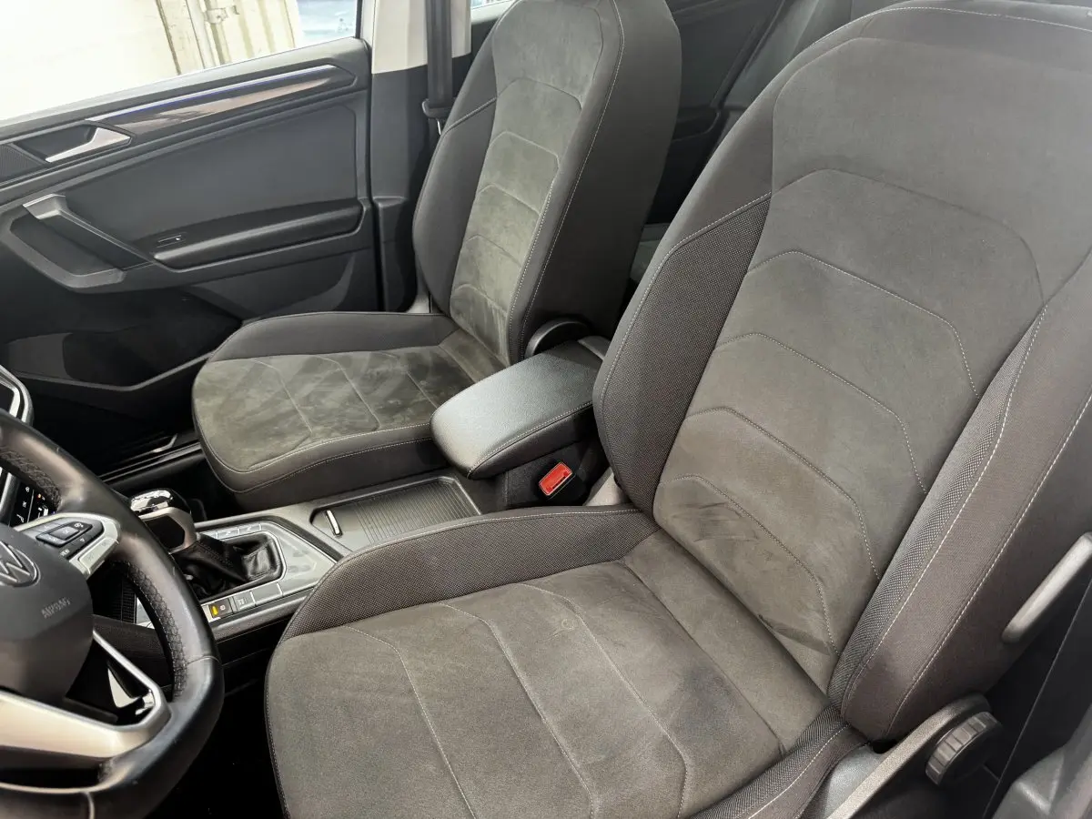 Vue intérieure côté conducteur du Volkswagen Tiguan gris, mettant en valeur les sièges tissu et alcantara et la console centrale.
