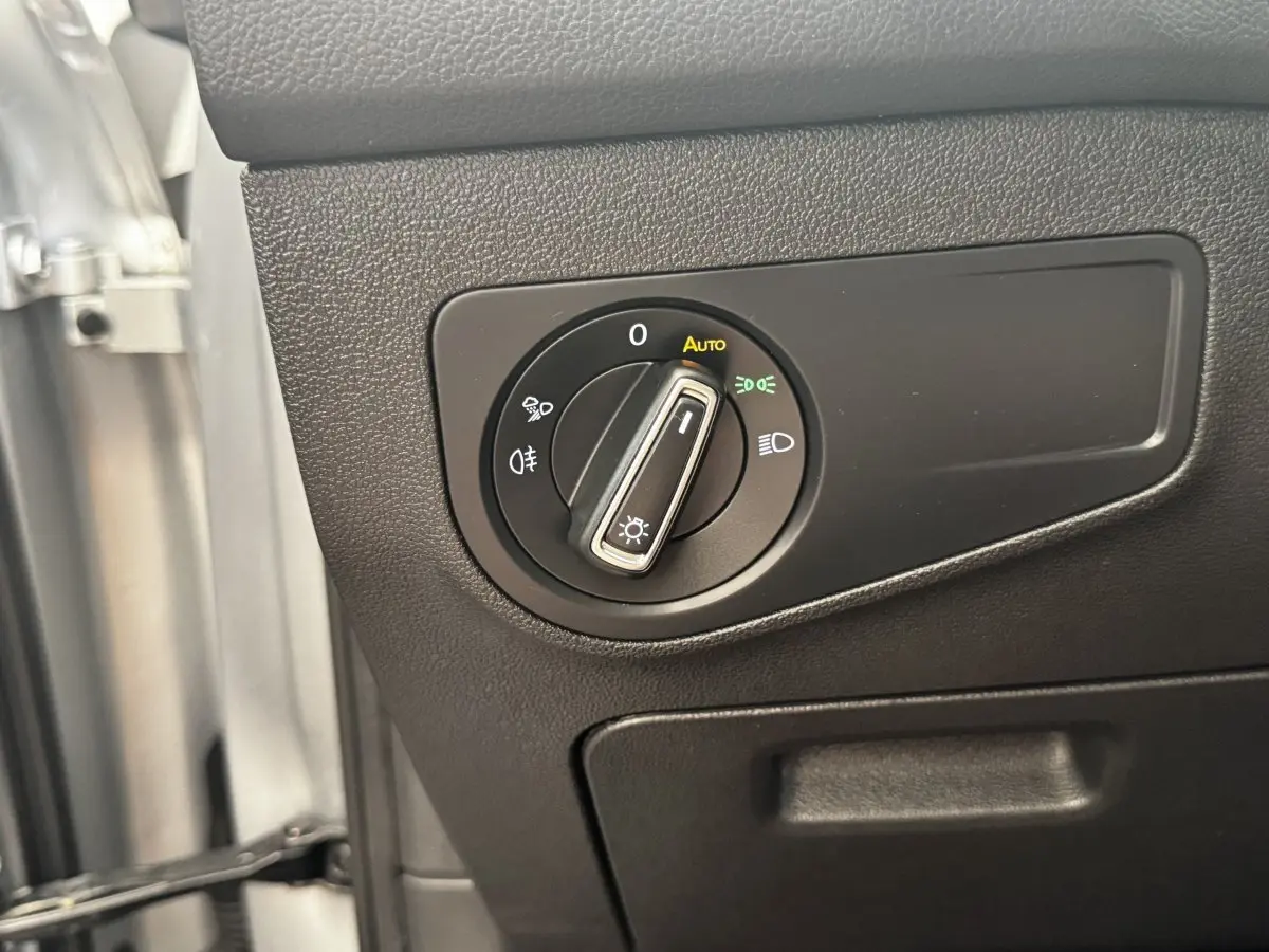 Gros plan sur le bouton de commande des phares à gauche du volant dans un Volkswagen Tiguan gris clair 2021.