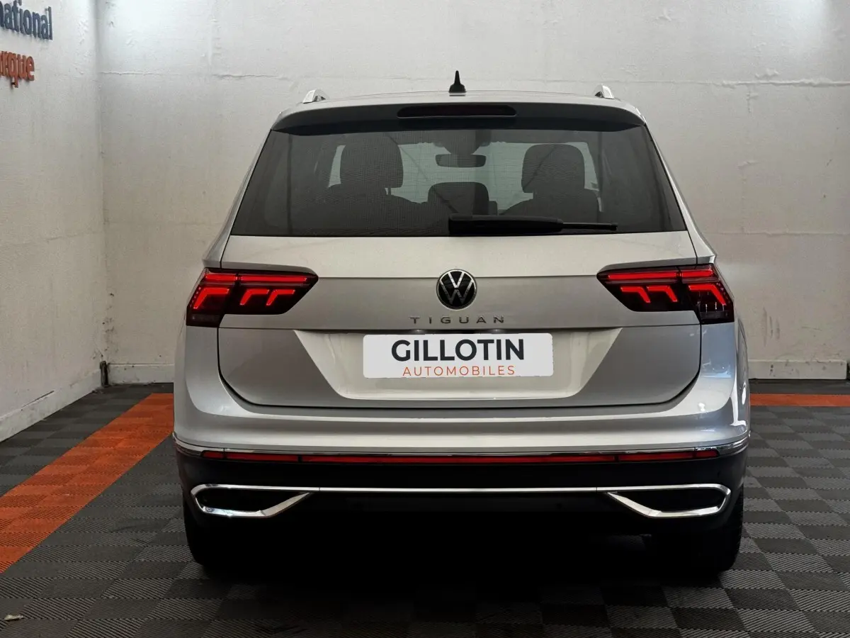 Vue arrière d'un Volkswagen Tiguan gris clair 2021 avec feux LED allumés et double sortie d'échappement chromée.