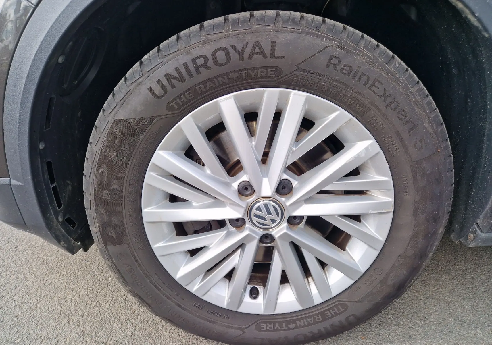 Gros plan sur la roue avant gauche d'un Volkswagen T-Roc Chêne Noir, avec jante alliage et pneu Uniroyal RainExpert 5.