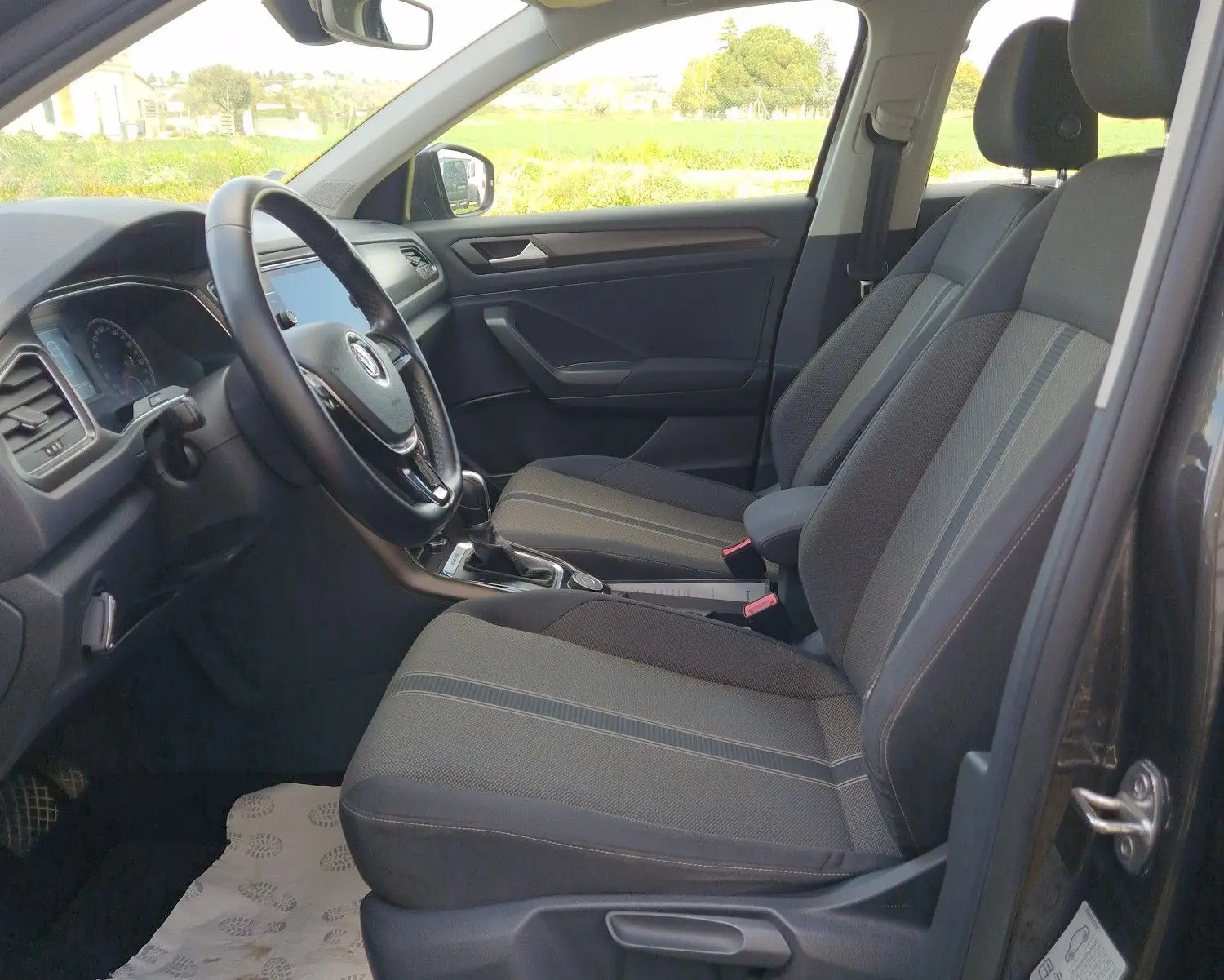 Vue intérieure côté conducteur du Volkswagen T-Roc Chêne Noir, mettant en valeur les sièges avant et le volant multifonction.