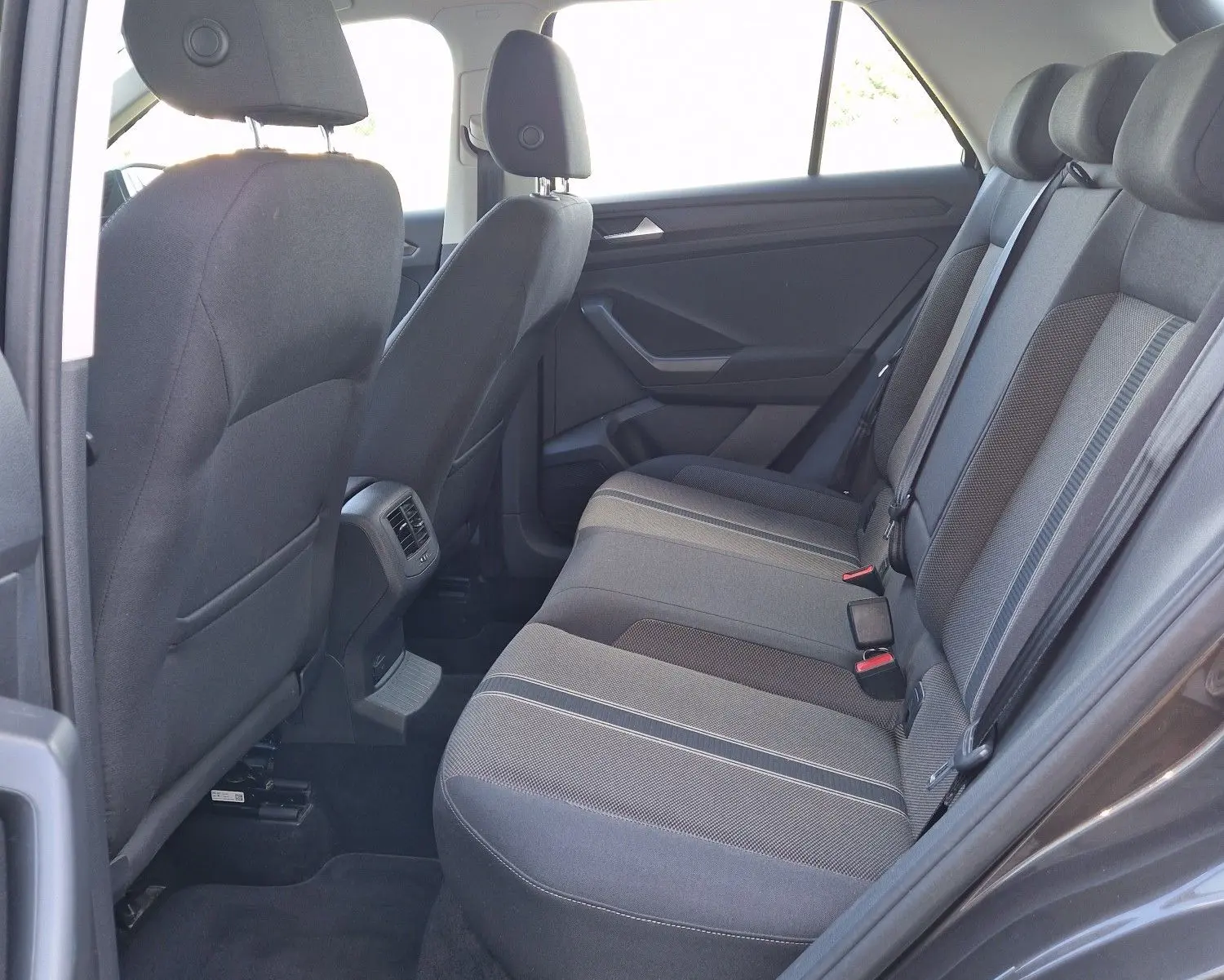 Vue intérieure côté droit arrière du Volkswagen T-Roc 2.0 TDi Lounge, sièges tissu gris avec détails rayés.