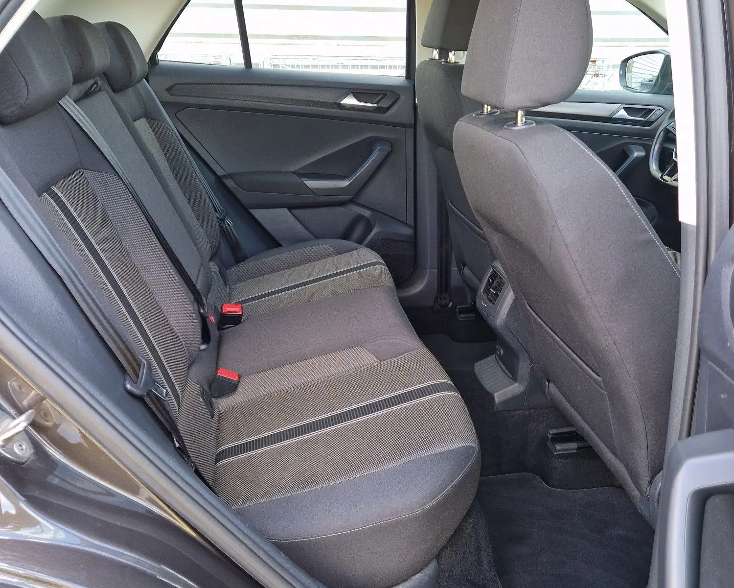 Vue intérieure côté gauche arrière du Volkswagen T-Roc chêne noir, montrant les sièges arrière en tissu et l'ouverture de porte.