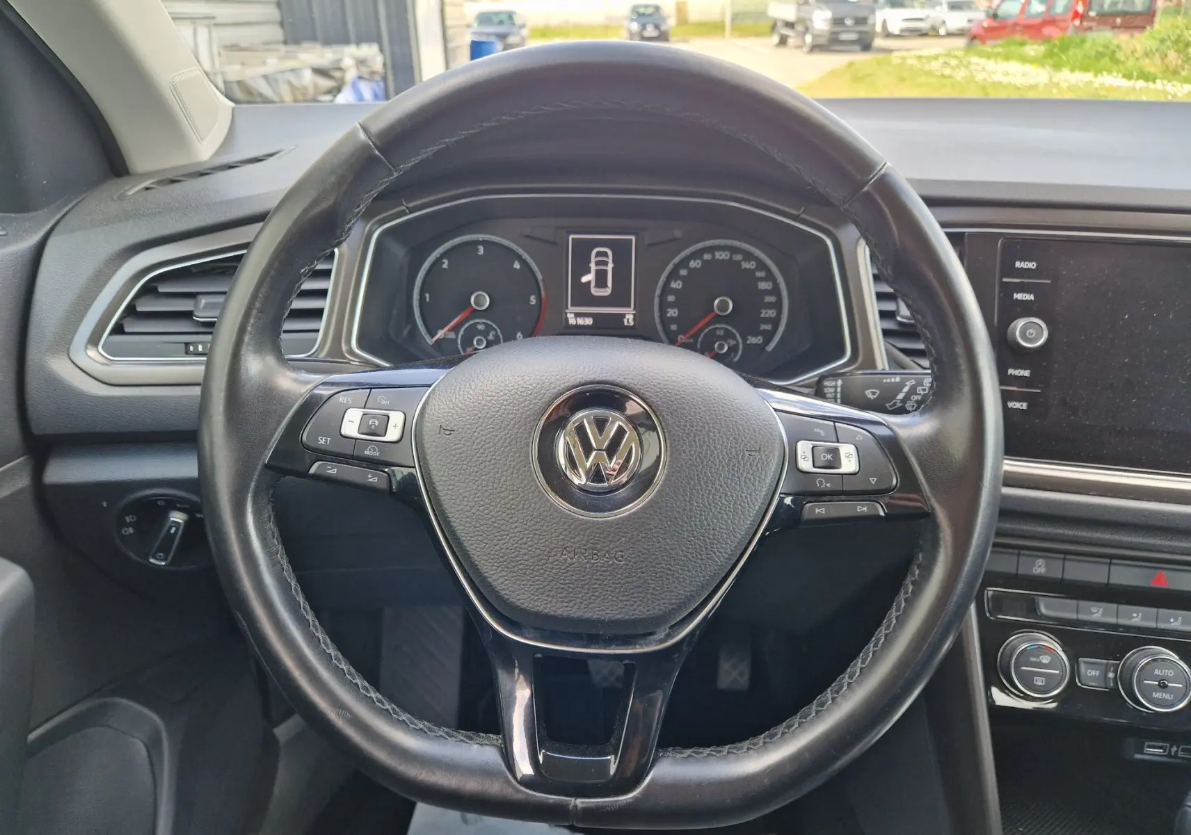 Volant en cuir noir de Volkswagen T-Roc 2.0 TDi 150 ch avec commandes intégrées et tableau de bord numérique visible.