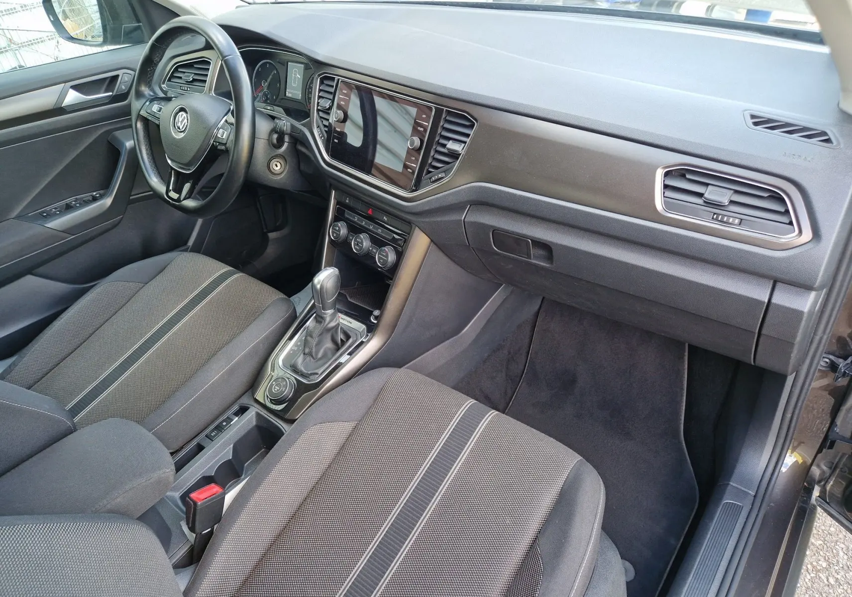 Intérieur avant droit du Volkswagen T-Roc chêne noir, volant cuir multifonction et console centrale avec boîte automatique.