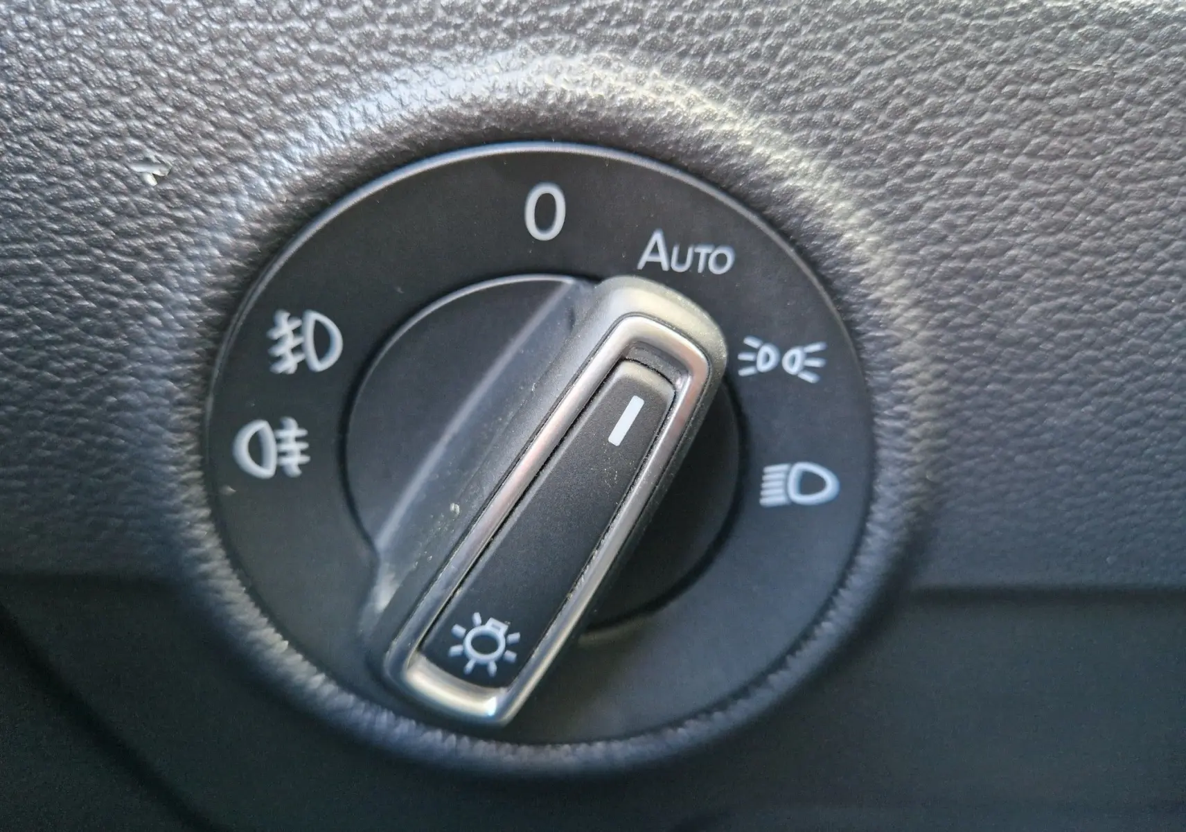 Gros plan sur le sélecteur de phares du Volkswagen T-Roc 2.0 TDi, bouton en position feux de croisement, entouré de pictogrammes lumineux.