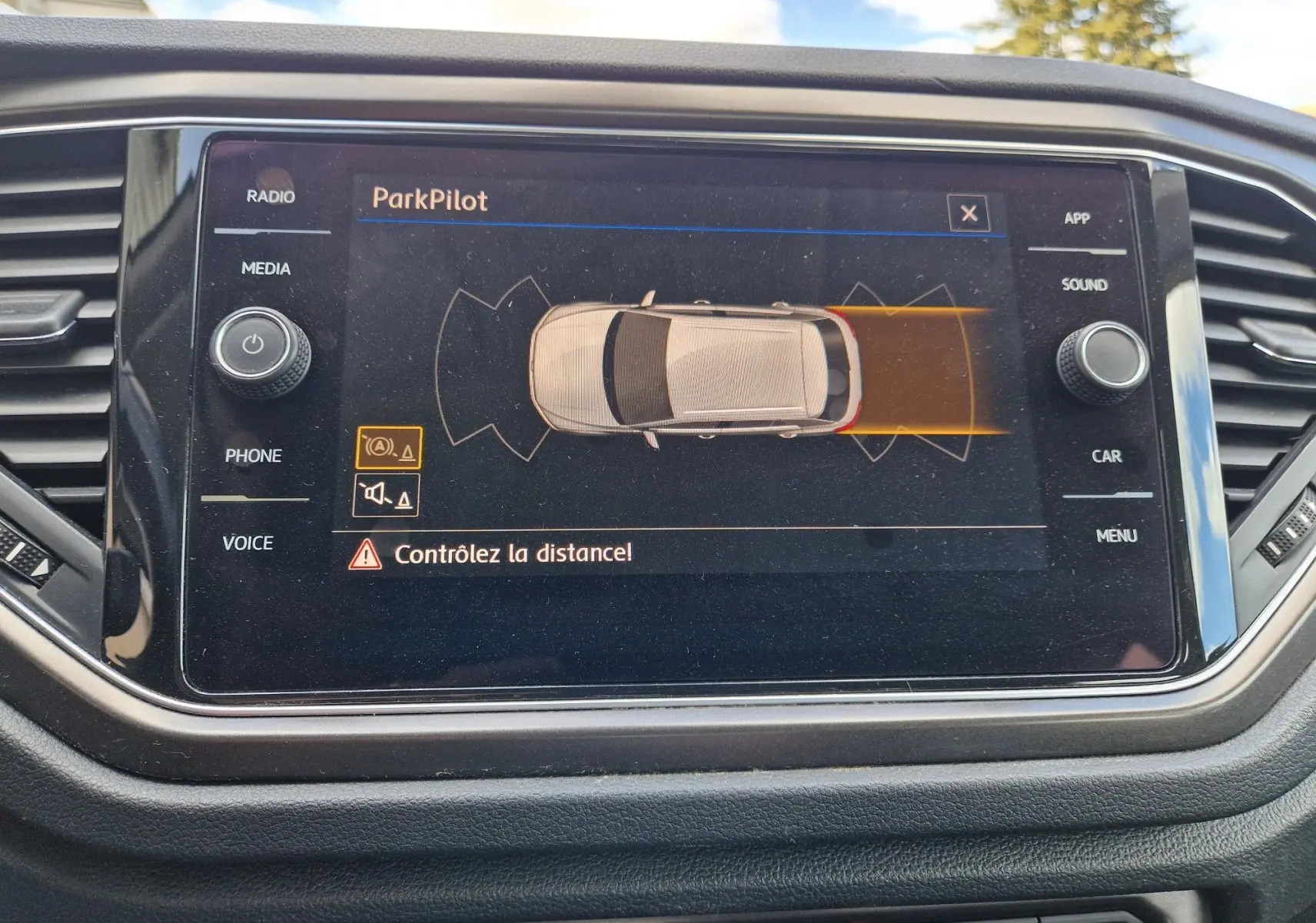 Écran tactile intérieur du Volkswagen T-Roc Lounge affichant l'alerte ParkPilot avec vue du véhicule en beige chêne noir.