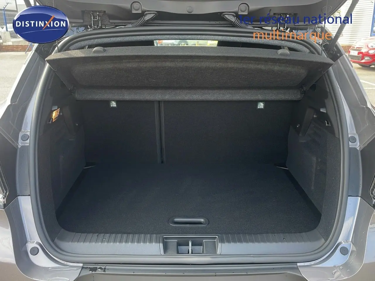Coffre ouvert du Renault Captur E-Tech gris Cassiopée métal avec toit noir, vue arrière montrant l'espace de chargement vide.