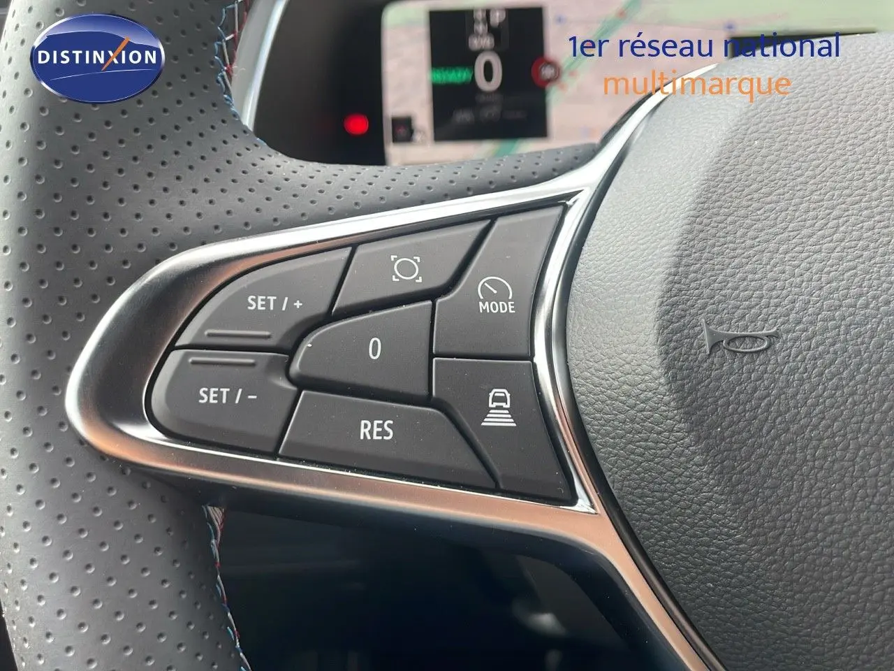 Gros plan sur les commandes au volant du Renault Captur E-Tech hybride 2025, avec cuir perforé gris et boutons fonctionnels.