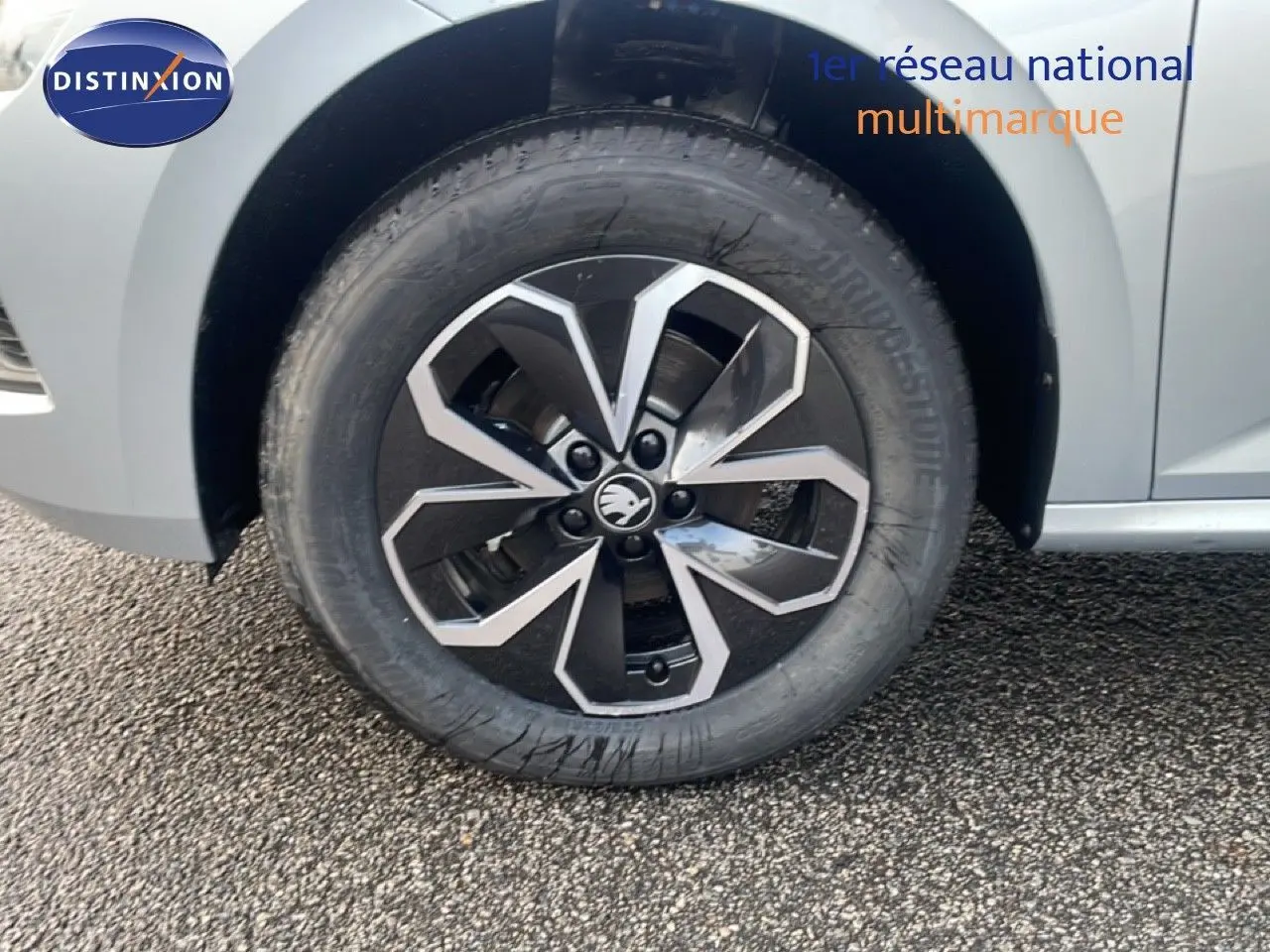 Gros plan sur la roue avant gauche d’un Skoda Kamiq gris argent métal avec jante alliage bicolore.