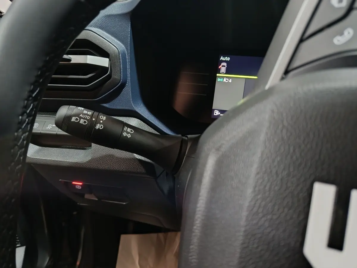 Gros plan sur la commande des phares et clignotants côté gauche du tableau de bord bleu foncé du Dacia Bigster 2025.