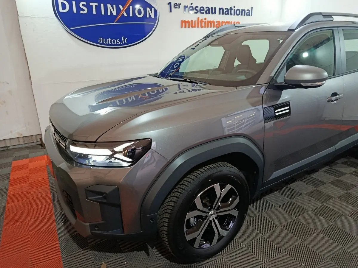 Vue 3/4 avant droit du Dacia Bigster gris foncé avec phares LED et jantes alliage au showroom Distinxion.