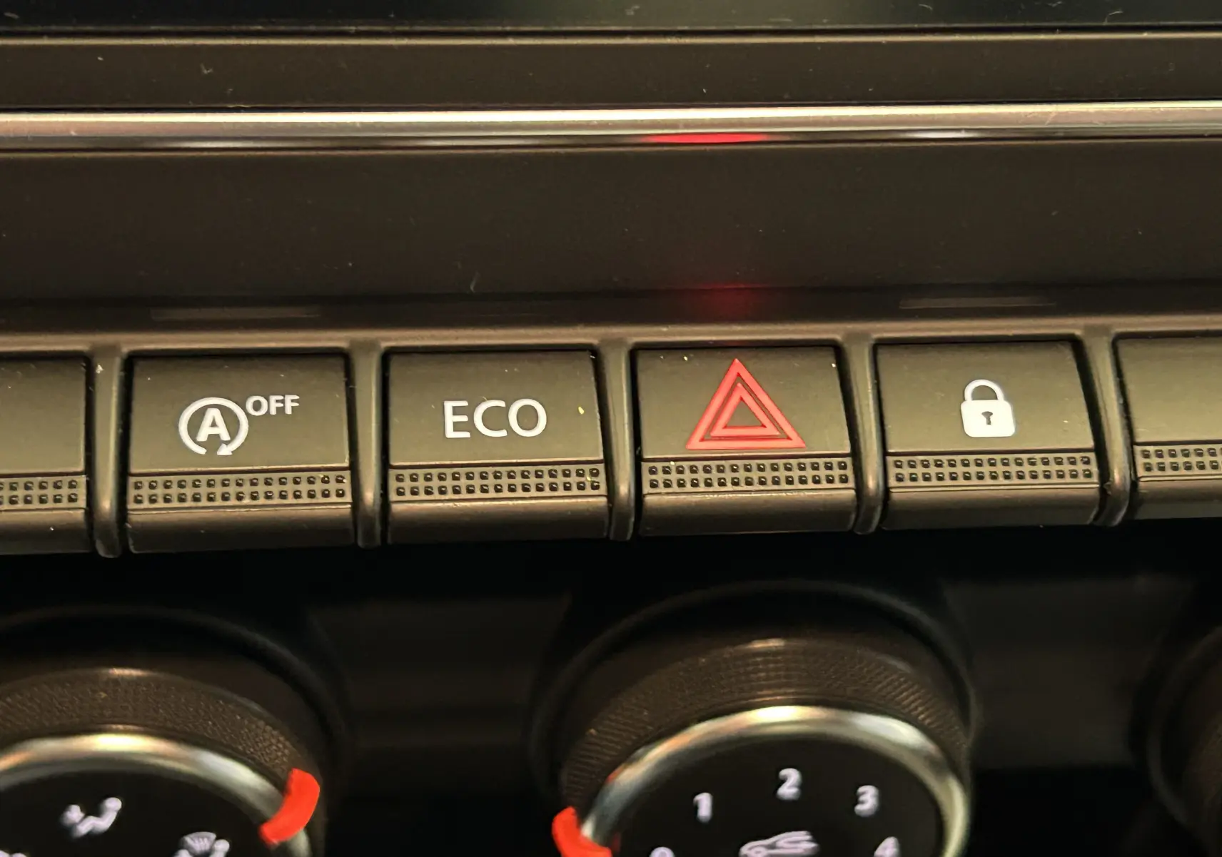 Gros plan sur les boutons de commande du tableau de bord de la Renault Clio V blanche, avec bouton ECO et alerte.