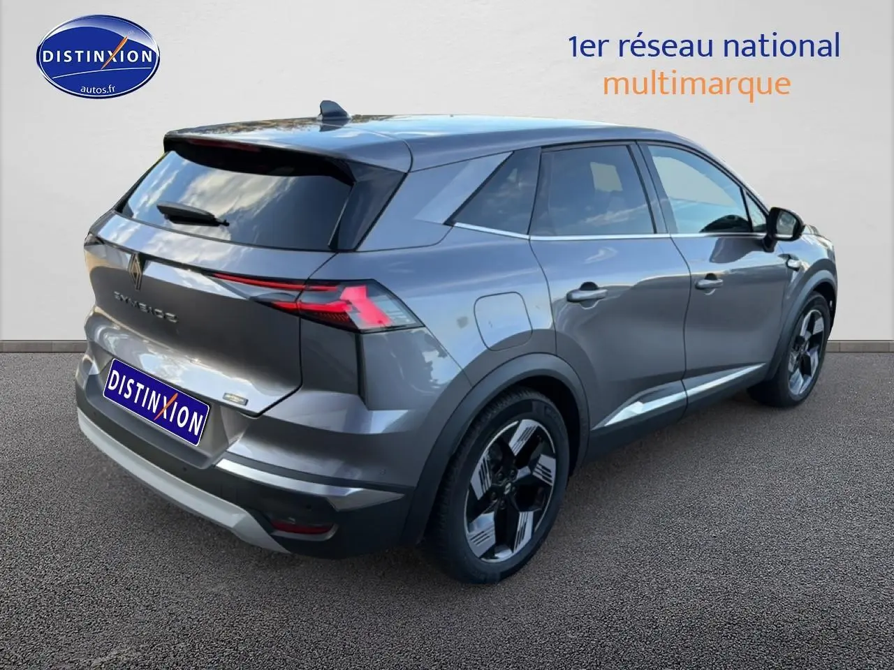 Vue 3/4 arrière droite d'un Renault Symbioz gris métallisé avec vitres surteintées et barres de toit visibles.