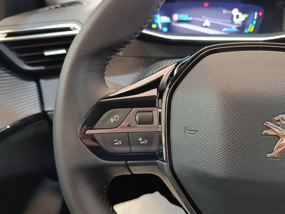 Gros plan sur le volant cuir noir de la Peugeot 208 électrique 2022 avec commandes vocales et tableau de bord numérique.