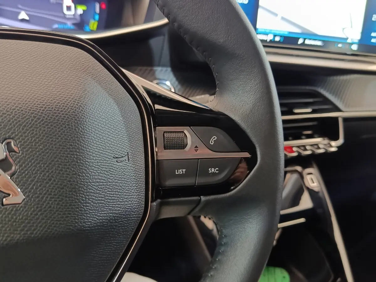 Gros plan sur le volant cuir noir de la Peugeot 208 électrique Roadtrip 2022 avec commandes intégrées côté droit.