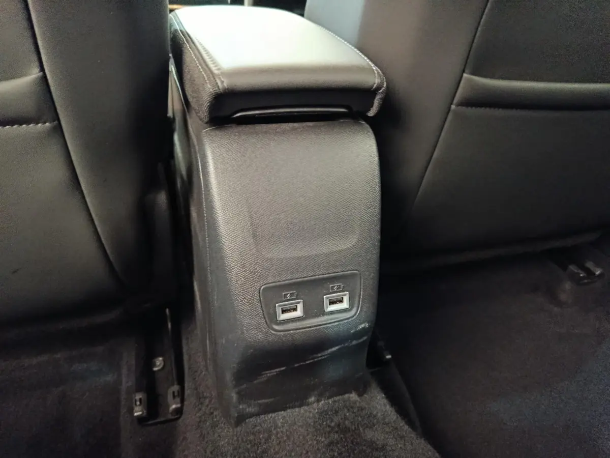 Vue rapprochée de la console centrale arrière noire avec deux ports USB dans l’habitacle d’une Peugeot 208 Electrique gris clair.