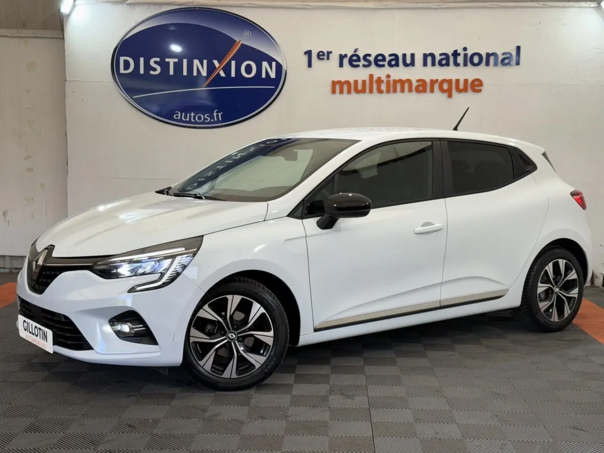 Renault Clio Evolution TCe 100 GPL blanche vue de profil droit en intérieur, avec jantes alliage et rétroviseurs noirs.