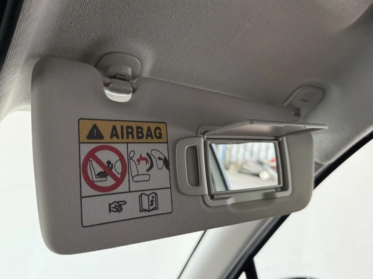 Détail du pare-soleil côté conducteur avec miroir ouvert et avertissement airbag dans une Renault Clio blanche.