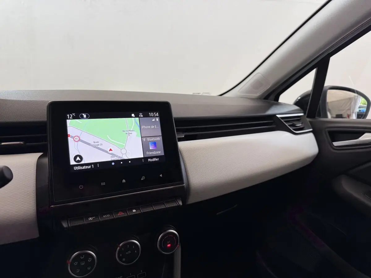 Tableau de bord côté passager de Renault Clio blanc 2023 avec écran tactile central affichant la navigation.