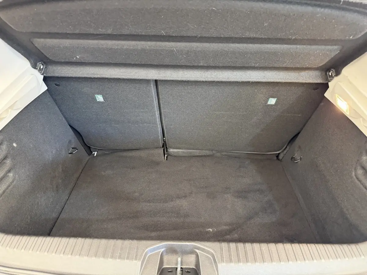 Coffre ouvert vu de face de la Renault Clio blanche 2023, intérieur noir avec banquette rabattable 2/3-1/3.